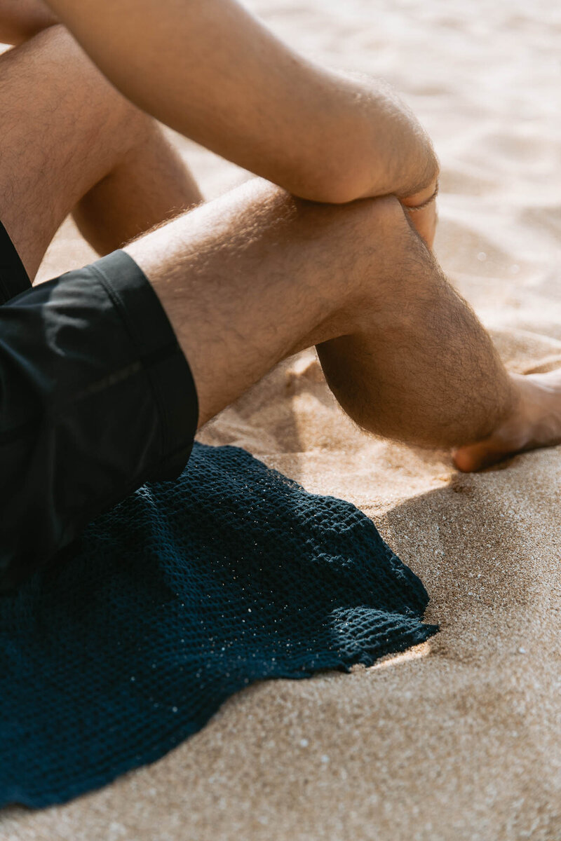 man-sitting-on-towel-at-beach