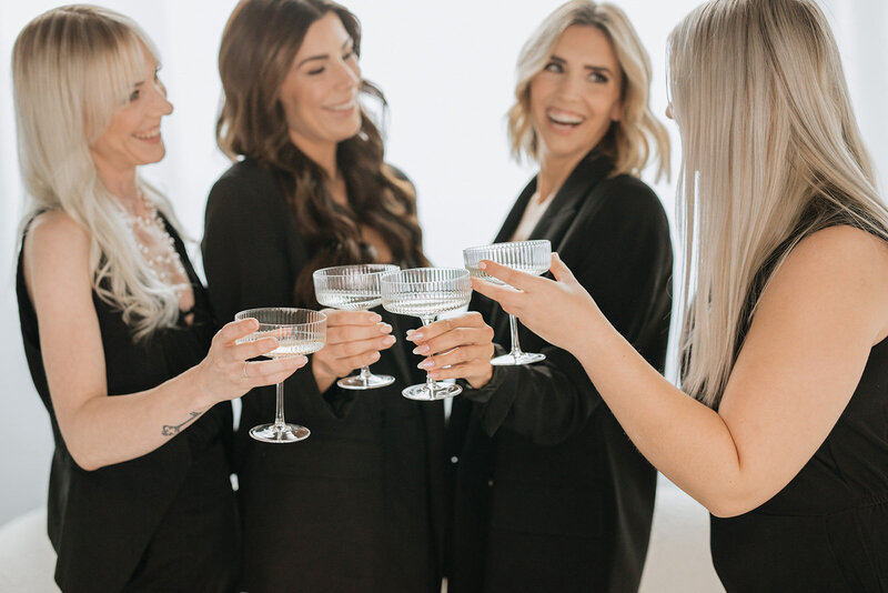 Photo of wedding planning company team cheersing with coupe glasses.