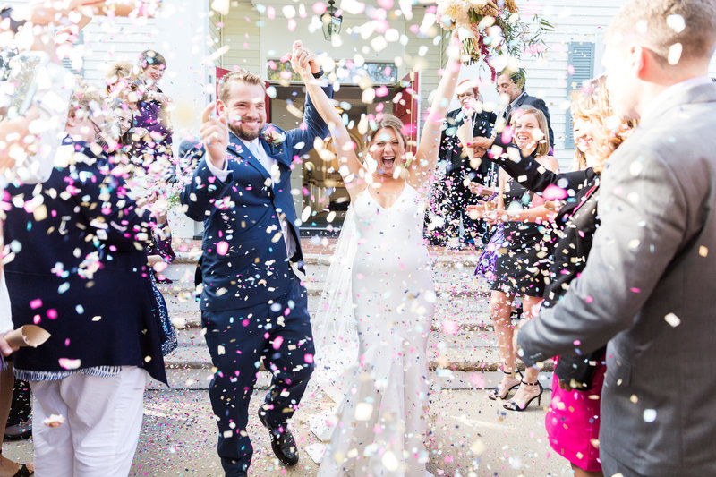 Bride and groom cheer and run through confetti after getting married