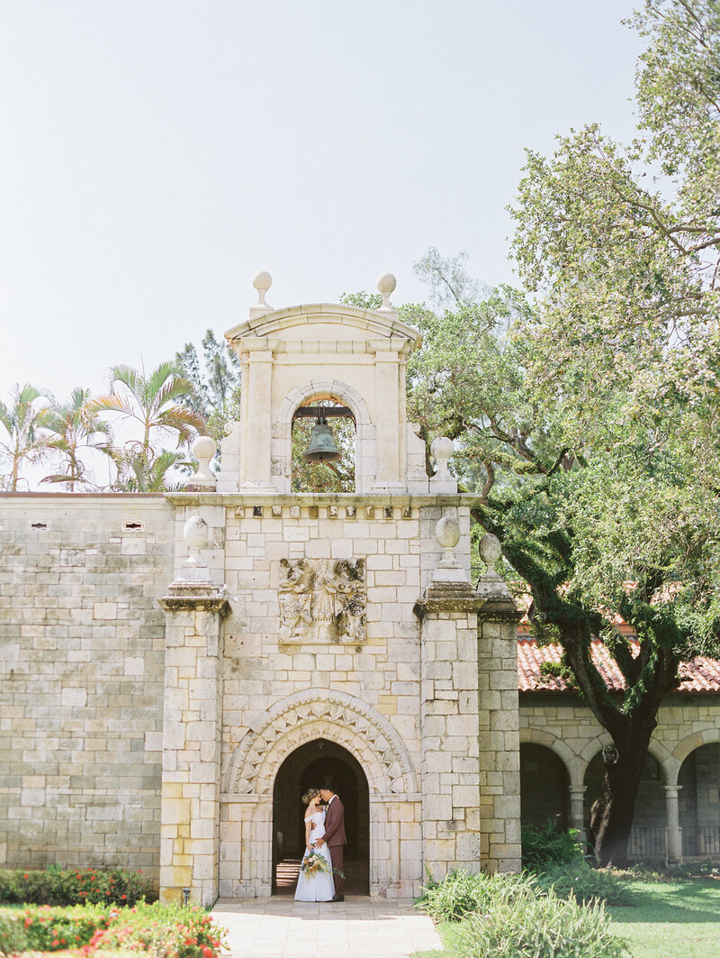 bride and groom under a stone arch at The Acient Spanish Monastery in Miami Florida
