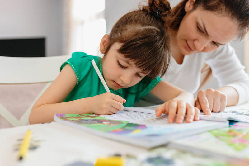 teacher scaffolding for young student at a table