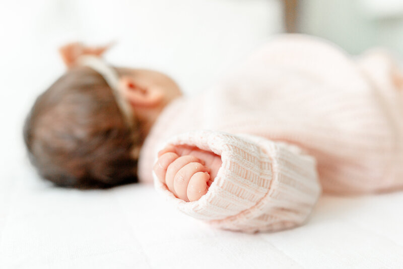 Ann Arbor Newborn Photographer takes photo of newborn baby girl on bed, close up shot of hand