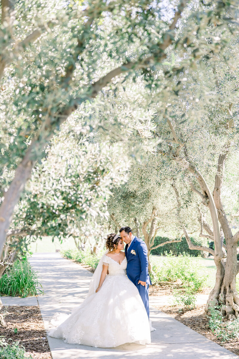 Bride and groom pose in a field of trees at their Clovis wedding