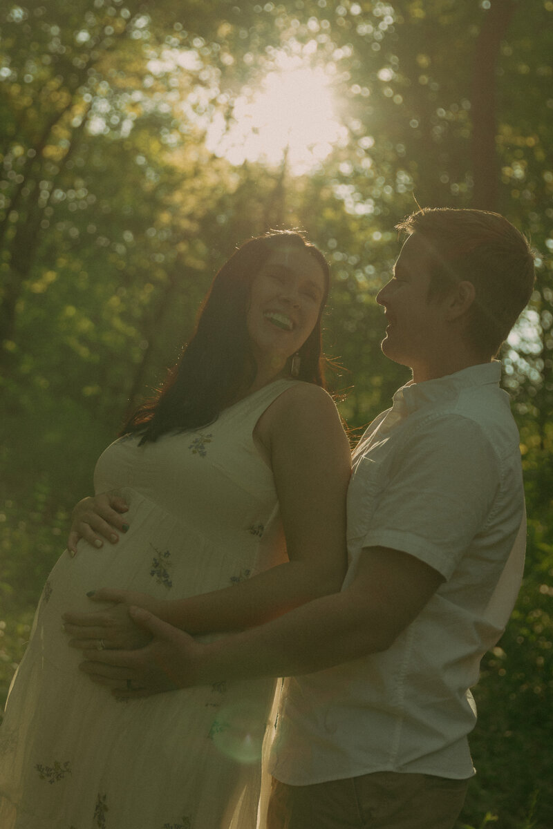 Newlyweds gaze into eachothers eyes on a brisk summer evening while the sun glares between their faces and her veil gets carried in the wind