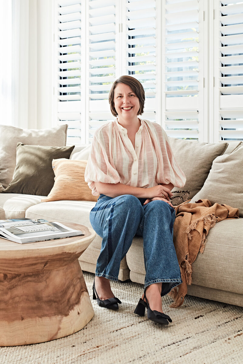 Interior designer Lisa Hunter smiling while seated in styled living room.
