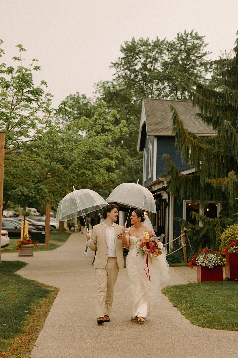 Bride and groom walking into Bayfield Town Hall with Umbrellas on wedding day