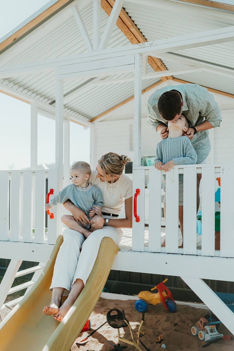 Lifestyle family photoshoot in Central West NSW with parents playing with their two young children on a backyard cubby house.