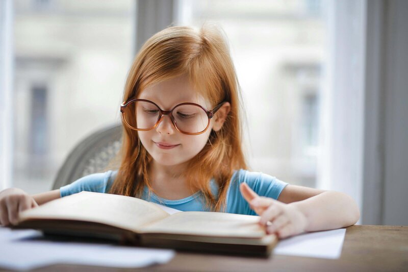 A young female student reading a book at her table