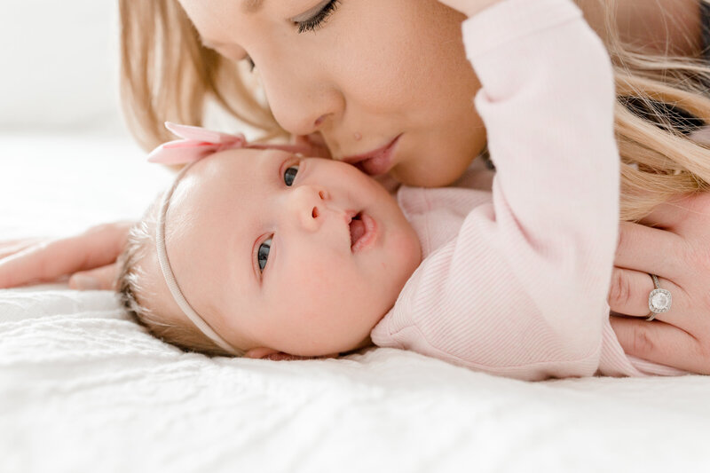 Minnetonka Mom kisses newborn baby on the cheek during newborn family