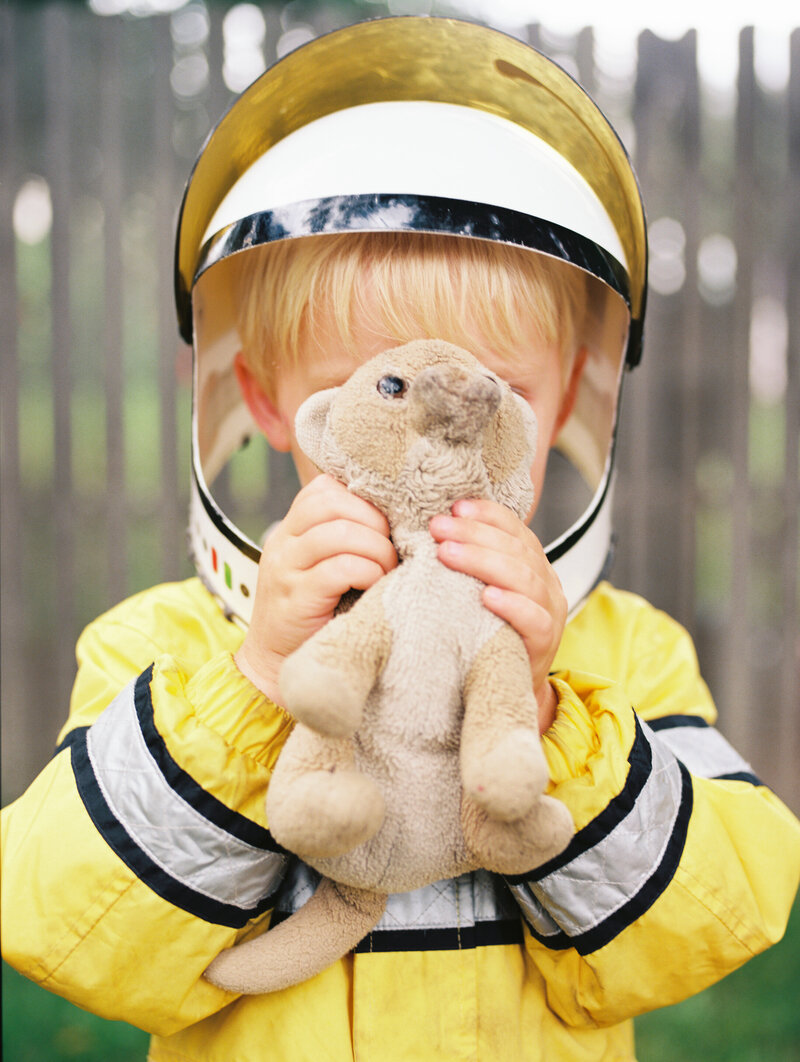 boys holds stuffed lion while wearing a costume