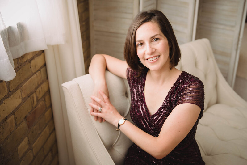 Flutist & Teaching Artist Sarah Weisbrod Sitting on a White Couch Wearing a Purple Dress