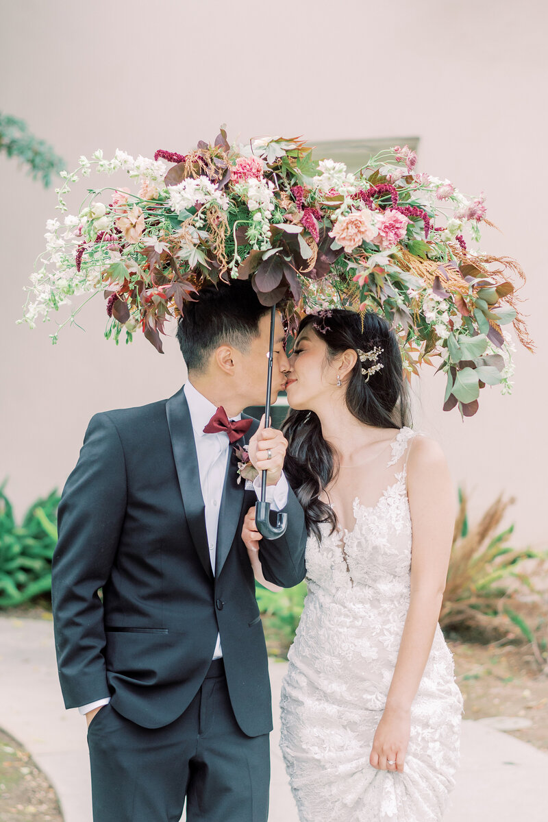 21-alisonbrynn-Radiant-LoveEvents-Maxwell-1-House-bride-groom-kissing-under-floral-umbrella-outdoors-romantic-elegant-timeless