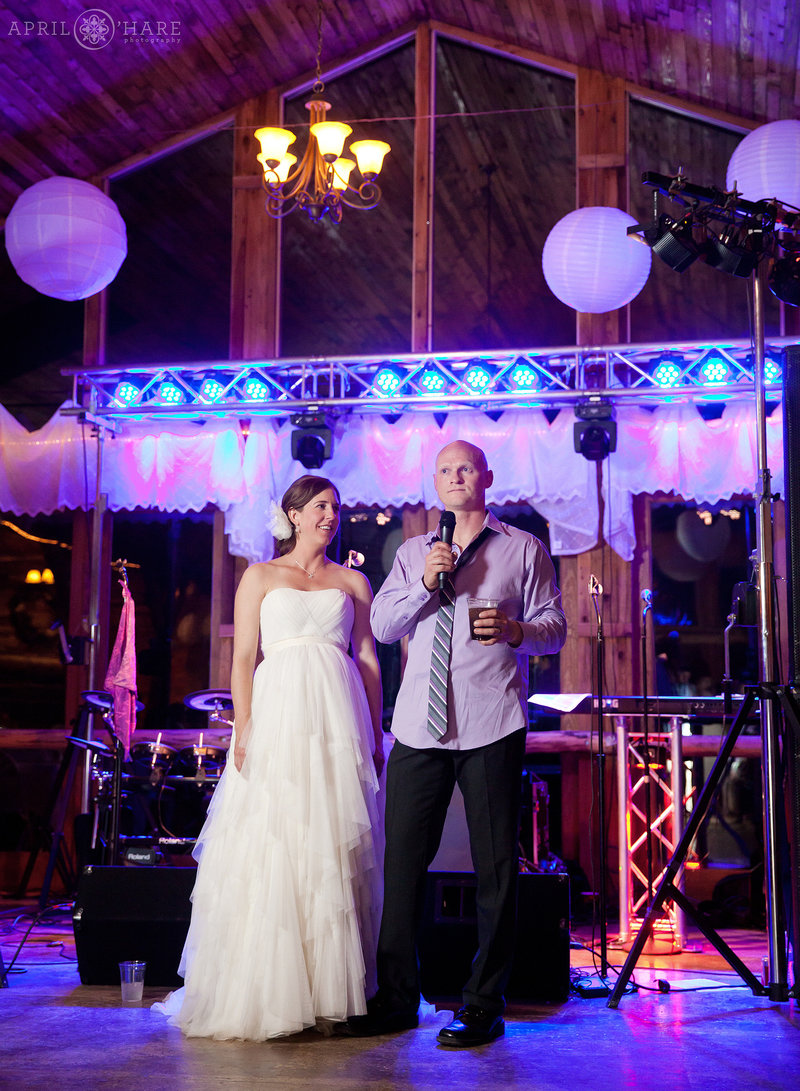 Bride and groom at barn wedding reception with purple lighting Colorado