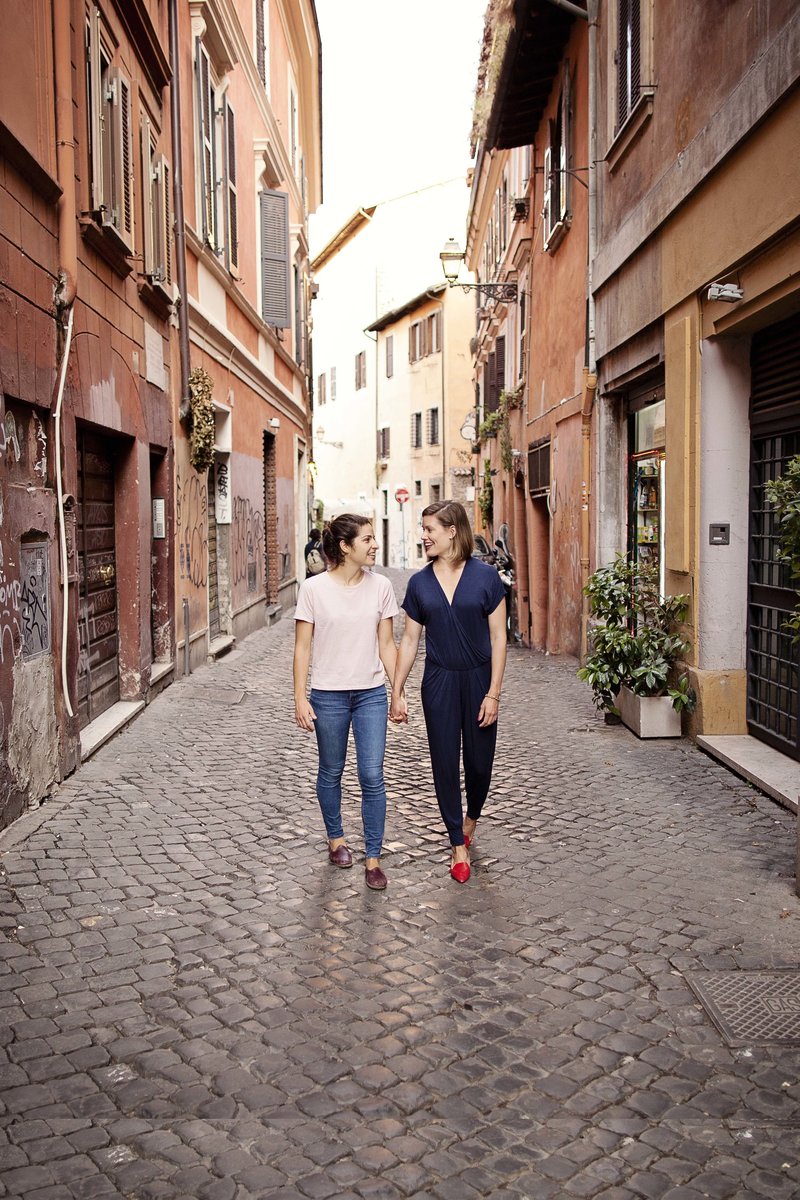 A couple holding hands on a classic roman street in Trastevere. Taken by Rome Photographer, Tricia Anne Photography.