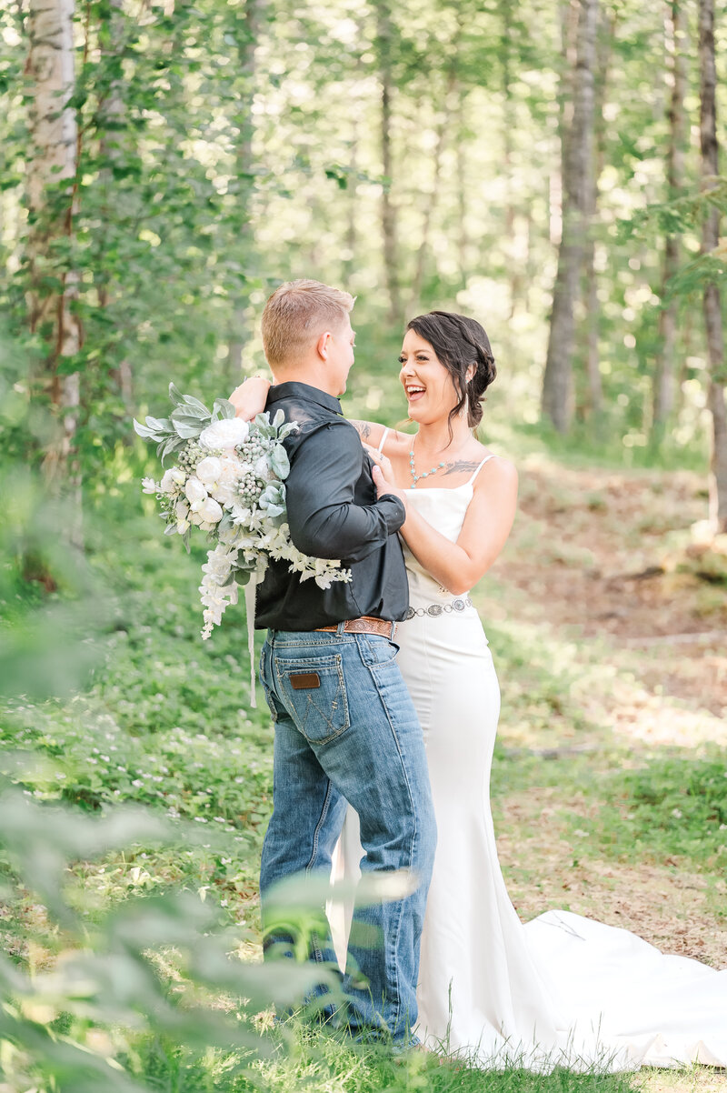 A brunette bride on her wedding day laughing with her new husband during their Alaska wedding by JoLynn Photography