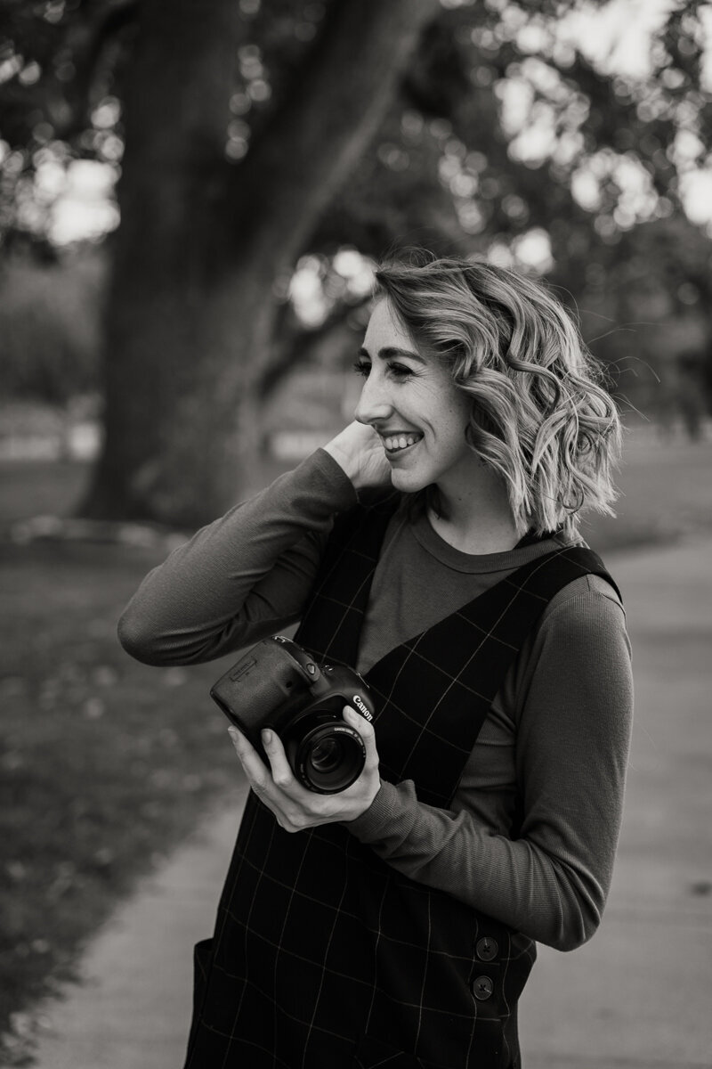 girl holds camera in park smiling