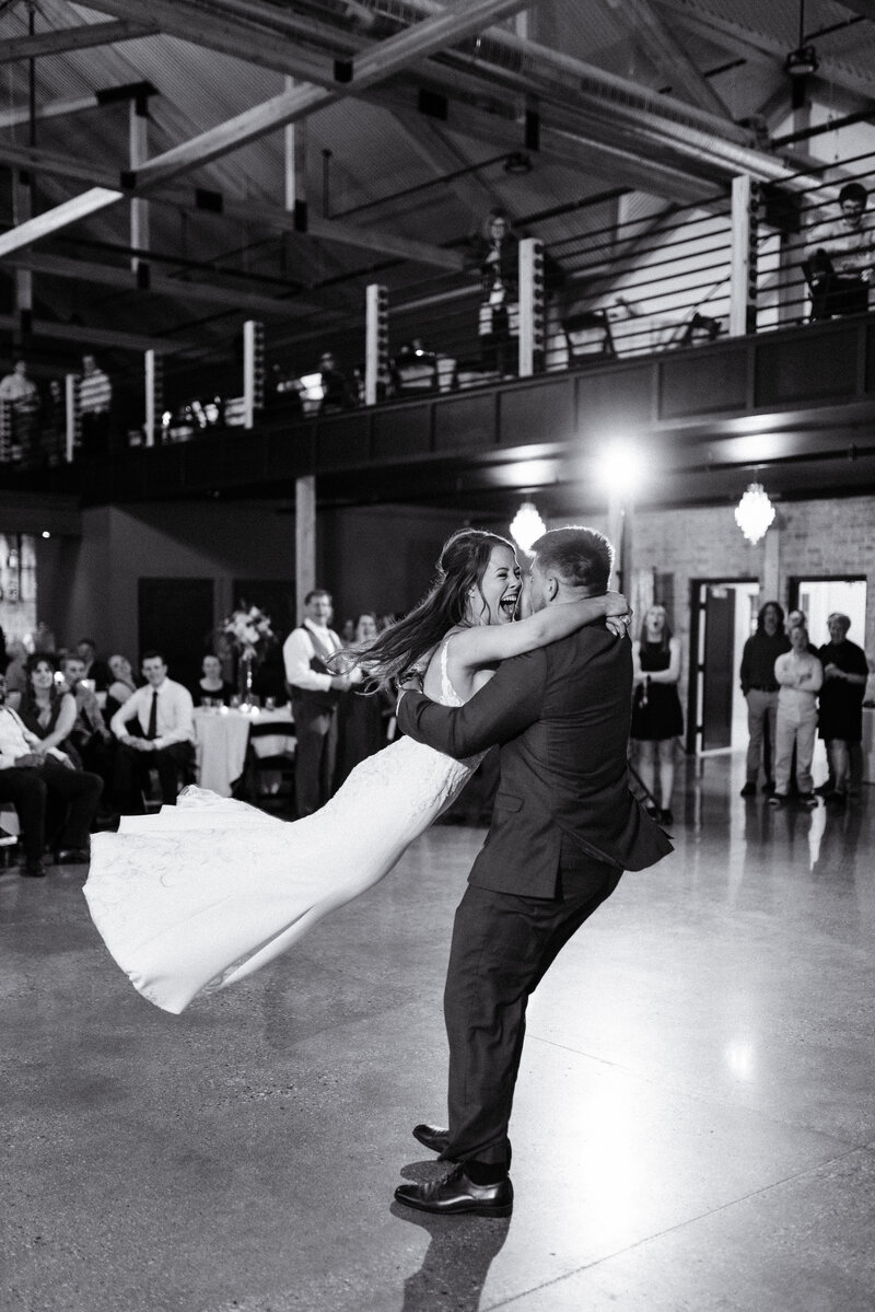Groom spins bride around the dance floor as she laughs with joy