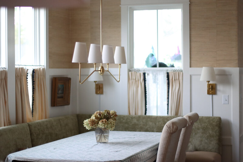 Elegant dining room in Charleston South Carolina featuring gold linear pendant chandelier, dried hydrangea bouquet, pinch pleat curtains, oil ship painting, grasscloth walls. 