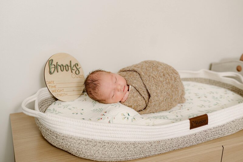 newborn baby boy laying on nursery table wrapped in brown