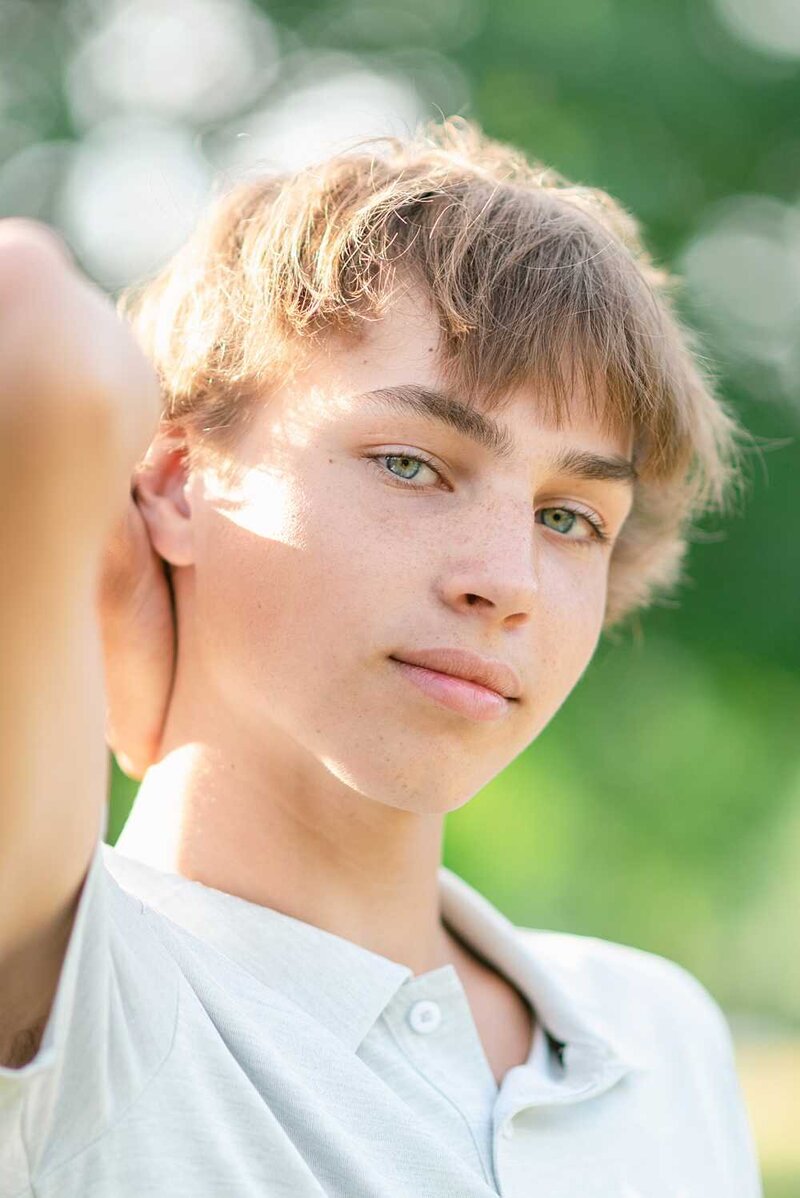 Teen boy with green eyes with his hand behind his head