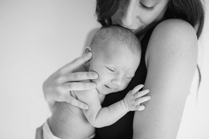 mom kissing newborn in arms