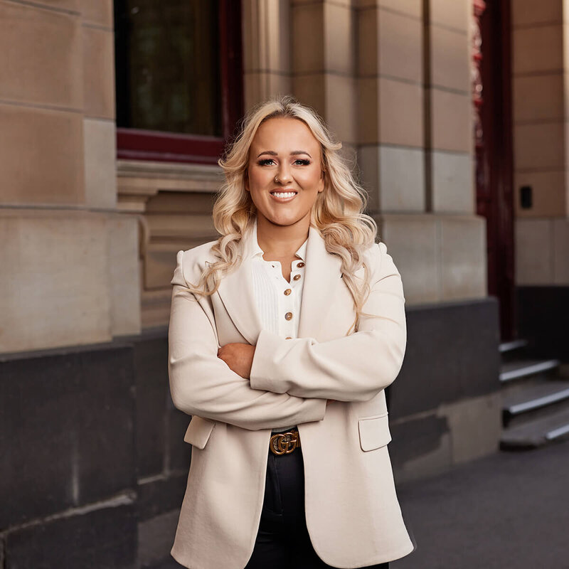 Blonde woman smiling standing in front of the Melbourne Supreme Court.