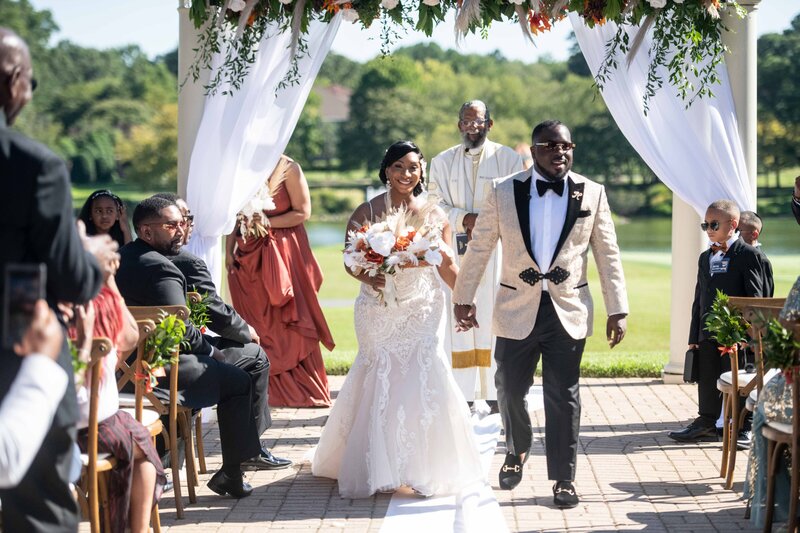 Bride and Groom exit wedding ceremony holding hands.