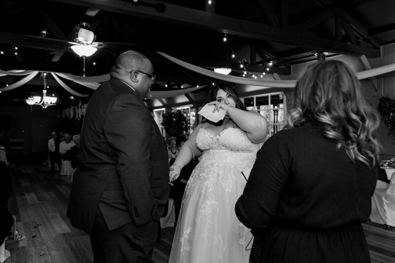 Emotional black and white photo of a bride crying during her Colorado wedding ceremony while holding her partner’s hand.