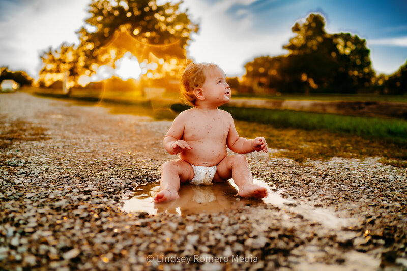 playful photo of baby playing in puddle outside at park in maurice, louisiana