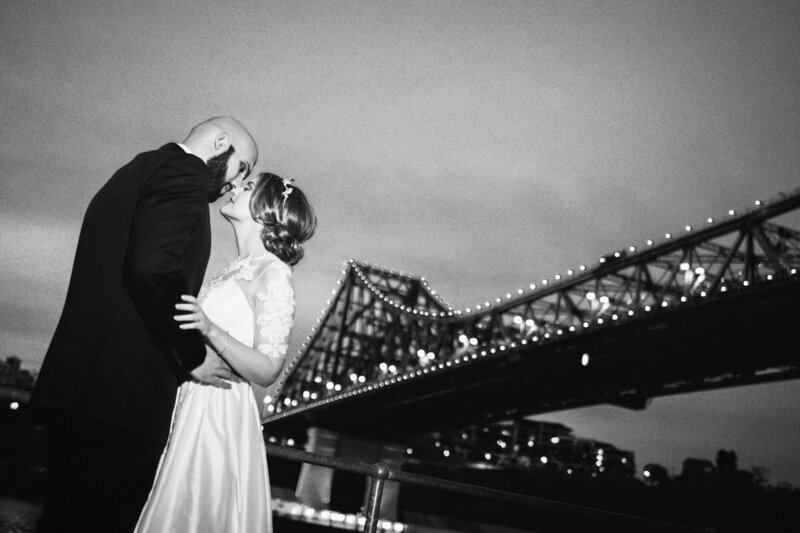 Wedding couple holding and leaning their heads towards each other under the bridge