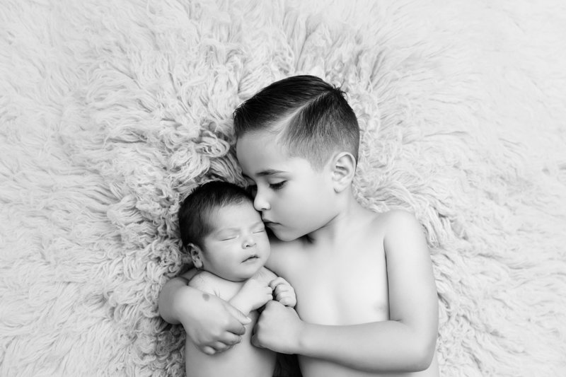 big brother sibling holding newborn