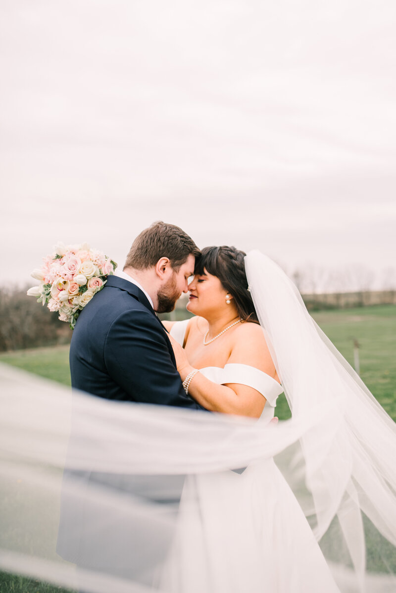 Couple embrace outside with flowing veil