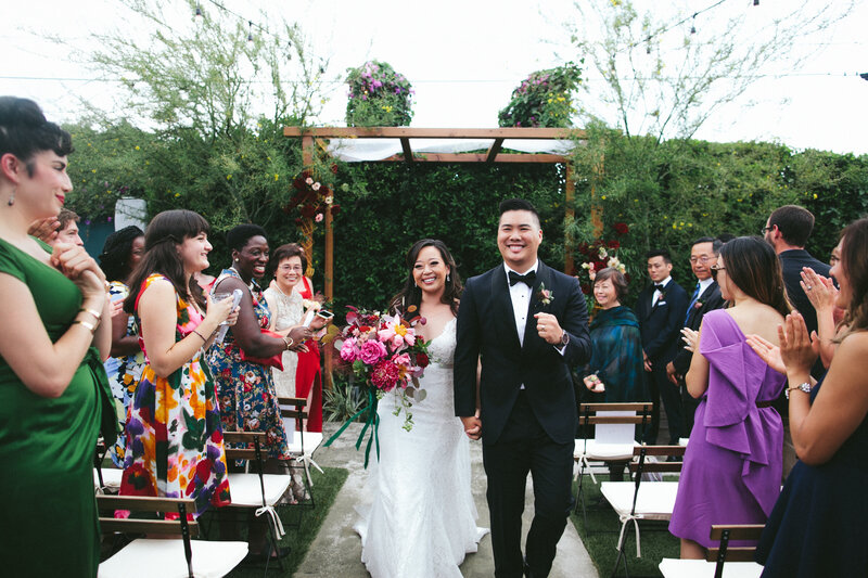 Bride and groom smile brightly while walking back down the aisle as a married couple
