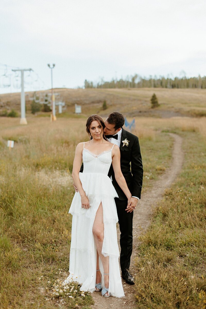 groom kissing bride with ski lift in background
