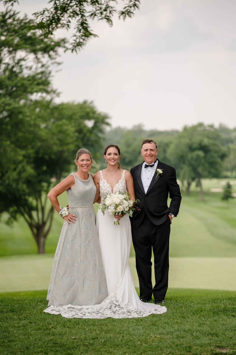 Bride and her parents outside on a golf course