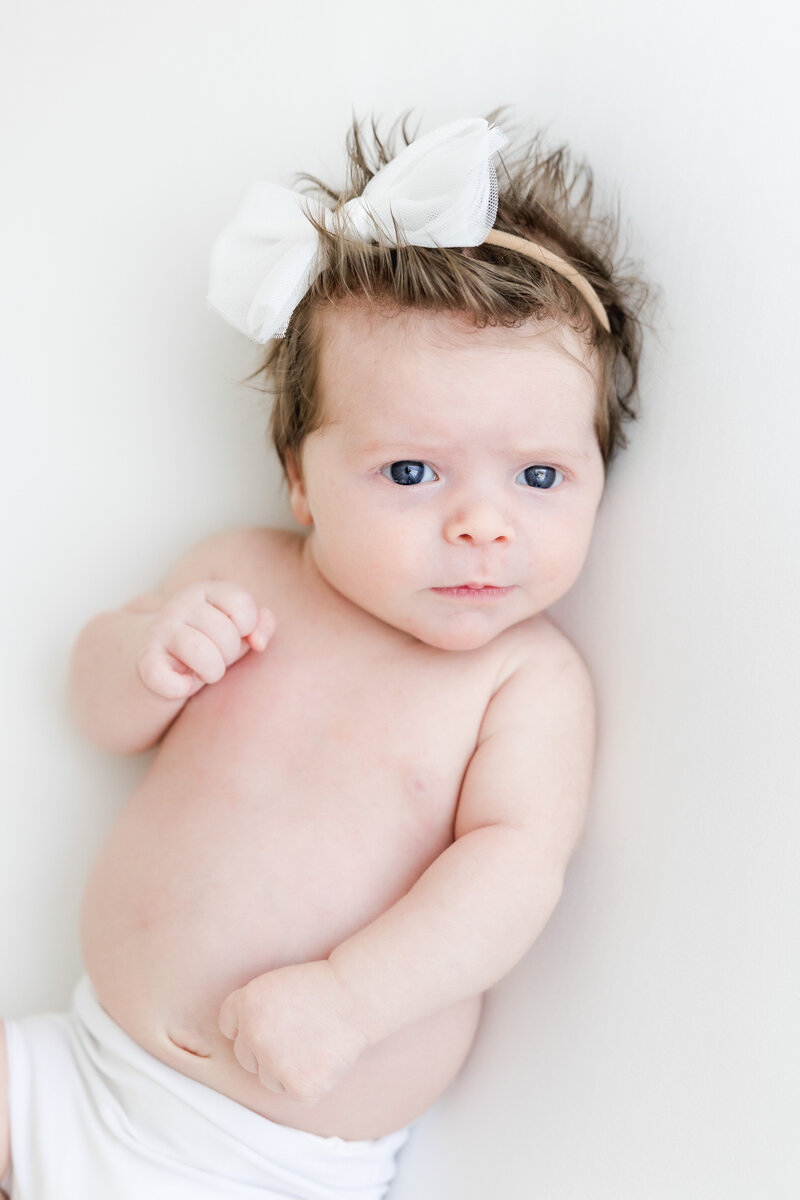 Newborn baby looks wide-eyed at the camera during newborn photography session