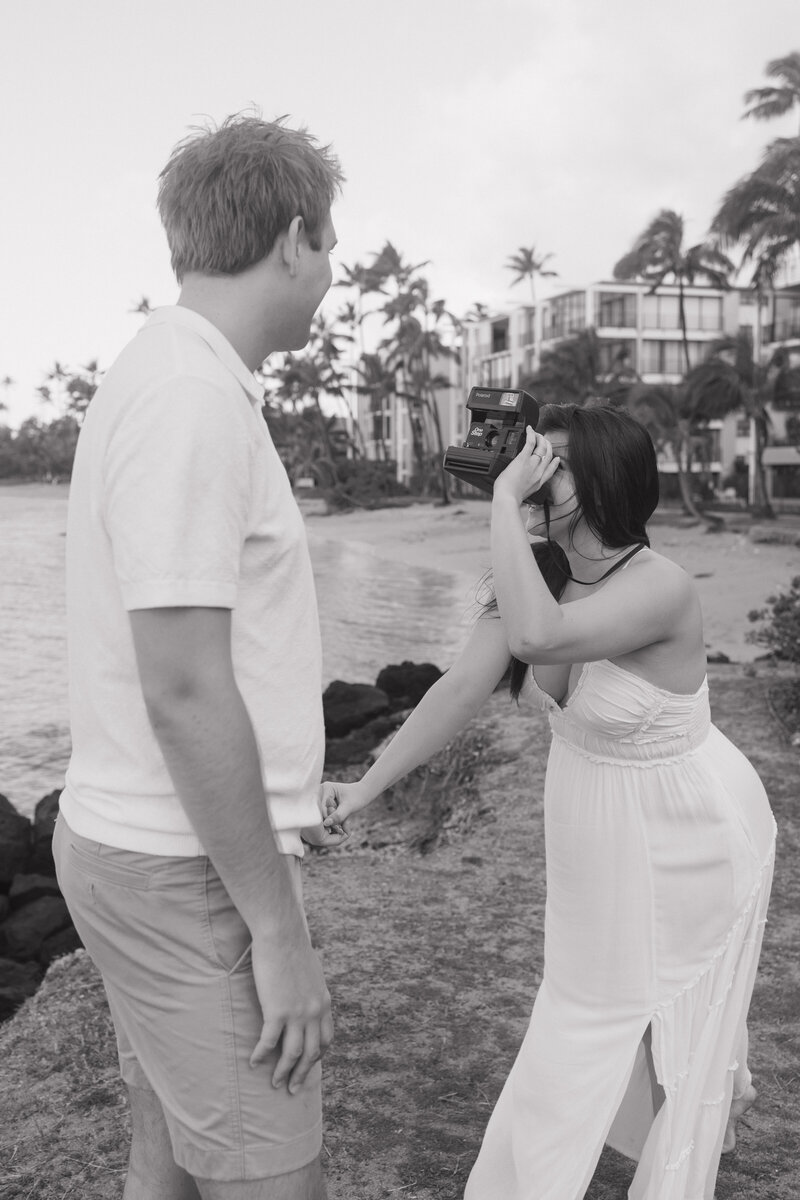 A newly engaged couple shares a candid and romantic moment at Waialae Beach, glowing with joy after his heartfelt proposal.