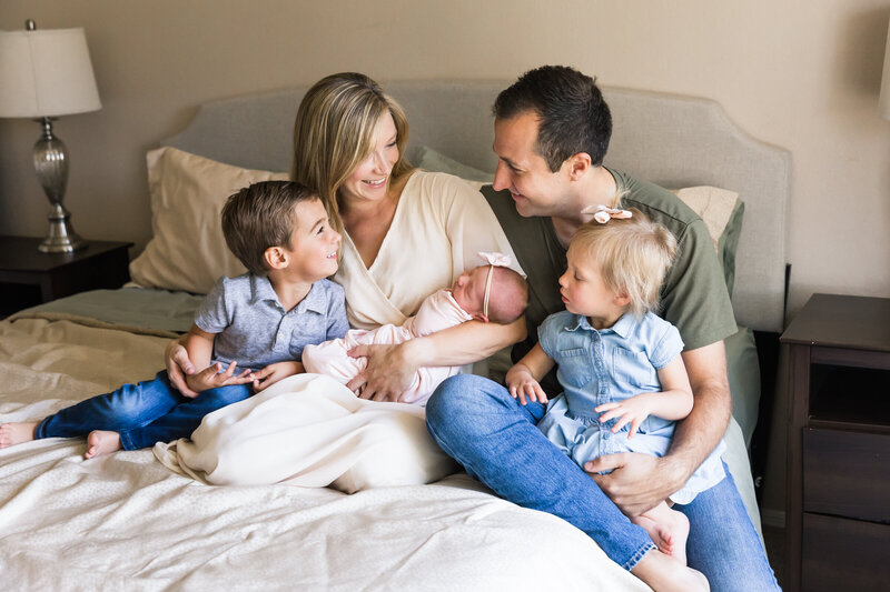 family smiling together holding newborn baby in lifestyle session