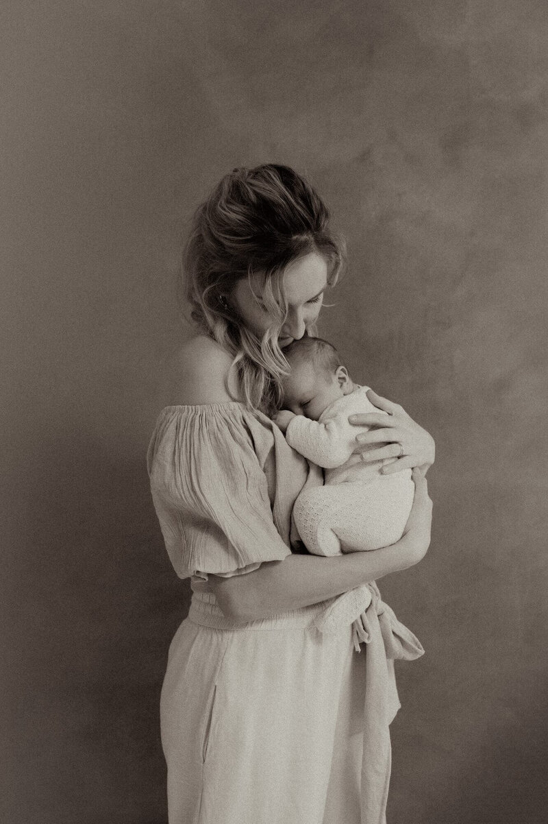 Mama omhelst baby tijdens newbornshoot in Atelier Oost Amsterdam