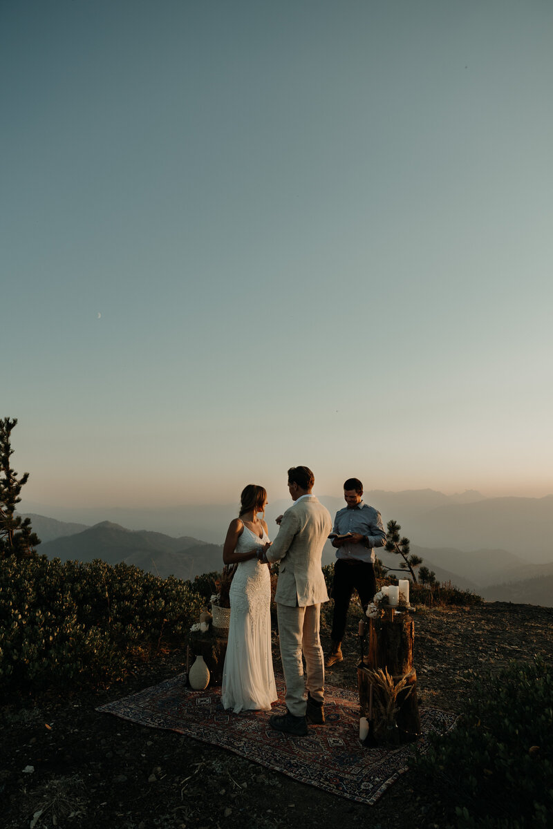 Elopement couple during golden hour ceremony with boho details overlooking the Enchantments and North Cascade mountains