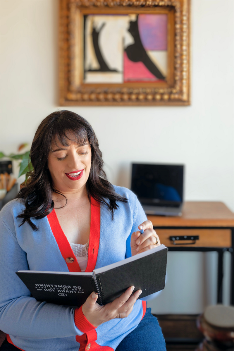 Renee Dalo makes notes in her notebook in blue cardigan