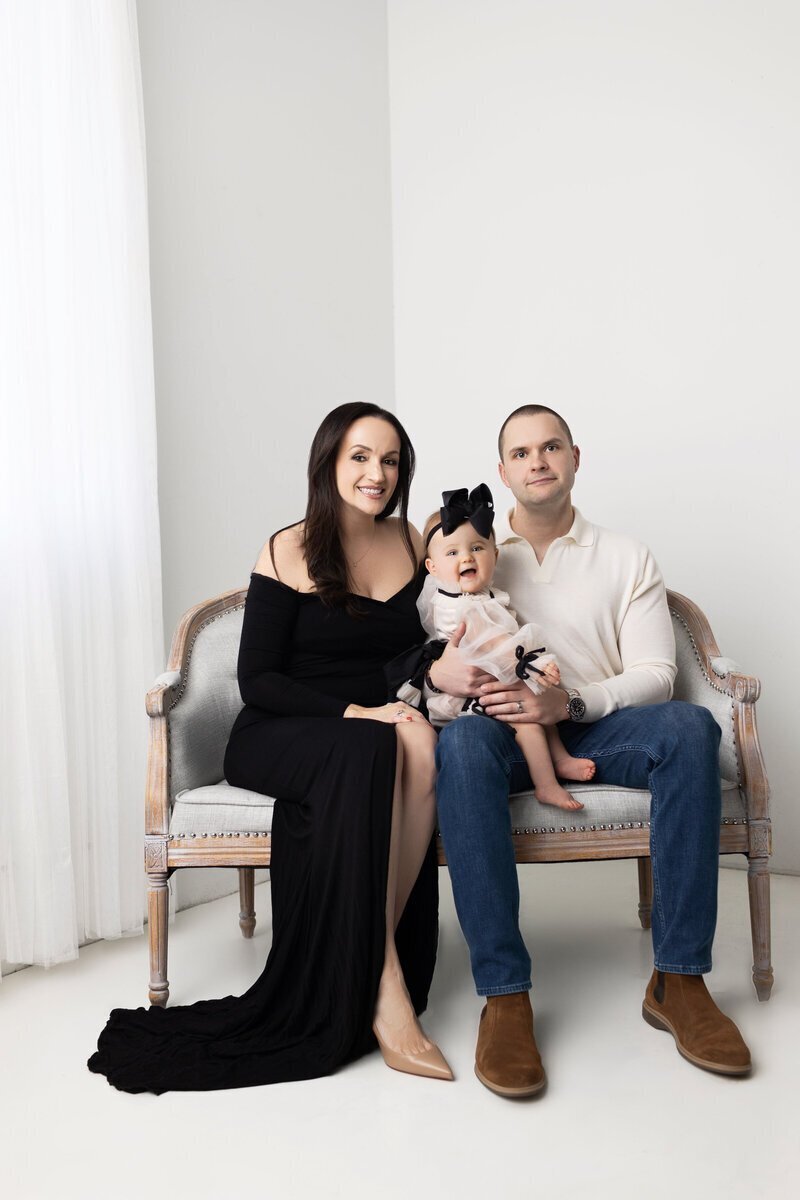 Parents with little girl sitting on bench by family photographer nj