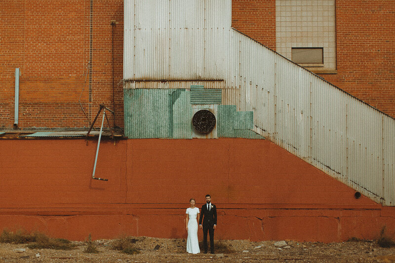 Bride and groom standing in front of an industrial  brick wall in St. Paul MN