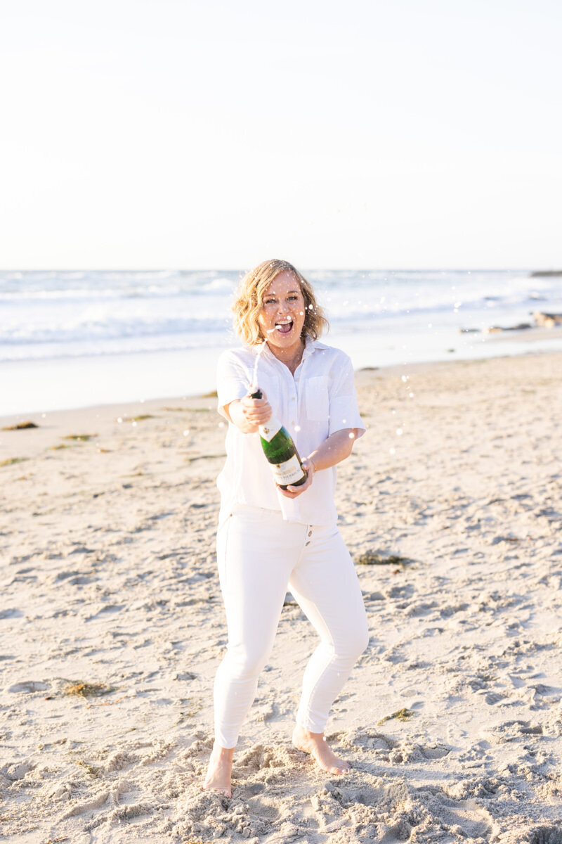 Lis Best popping a bottle of champagne on the beach