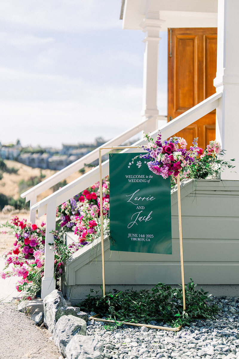 Editorial-style wedding signage surrounded by fresh florals welcomes guests to a San Francisco wedding near the California coast.