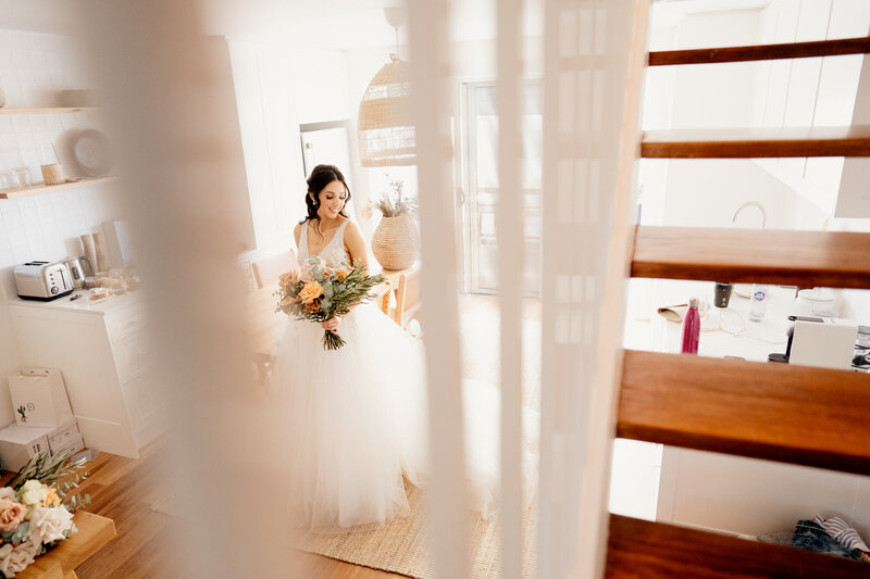 Bride posing downstairs while holding her bouquet of flowers