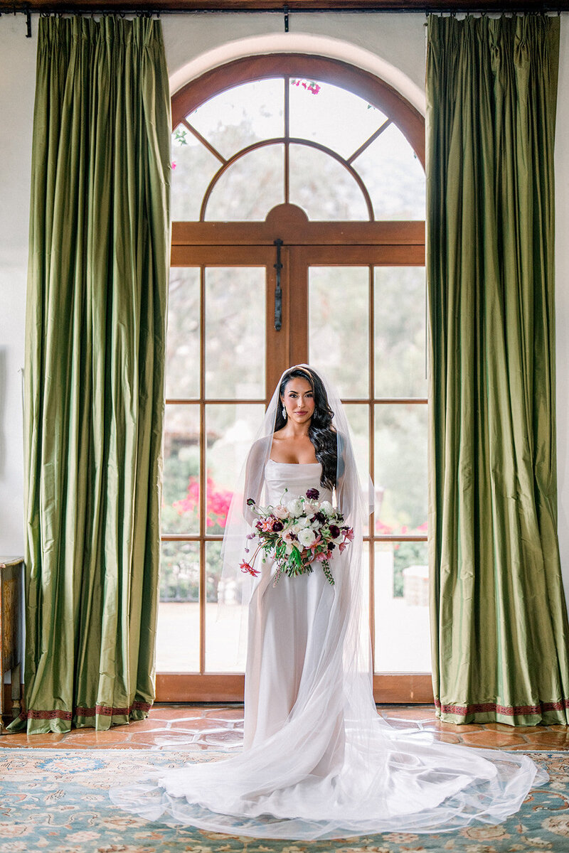 Bridal portrait in window light with dramatic green drapery captured by a film wedding photographer in Simi Valley California