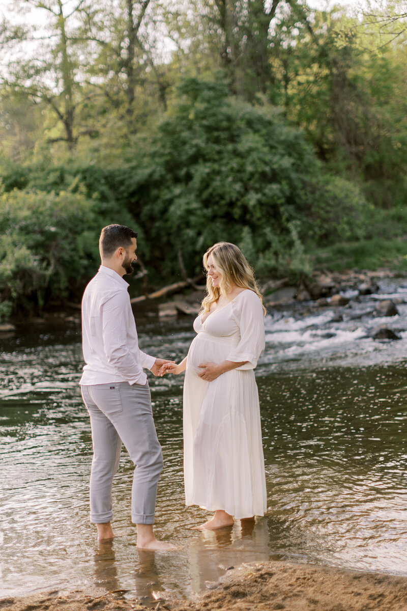 Husband holds his wife's hand during maternity portrait session