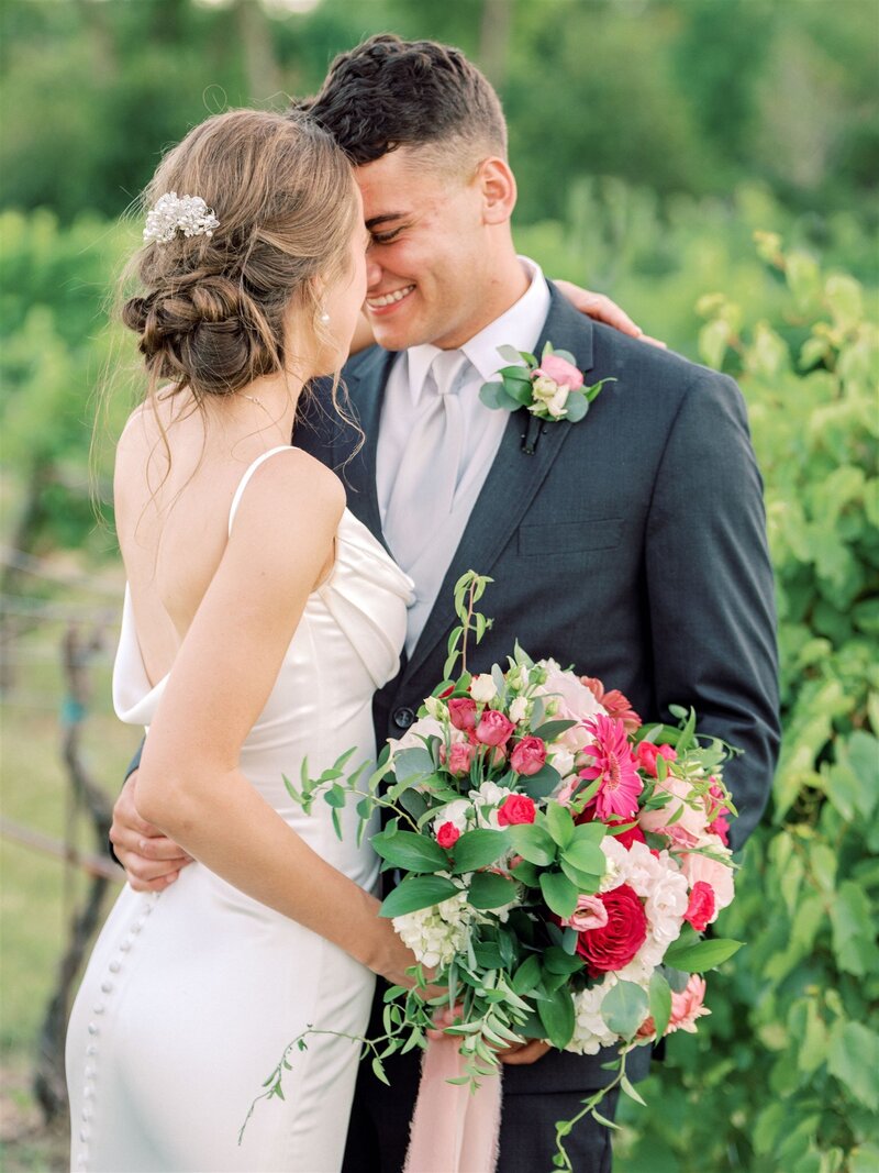 bride and groom holding bouquet in vineyard