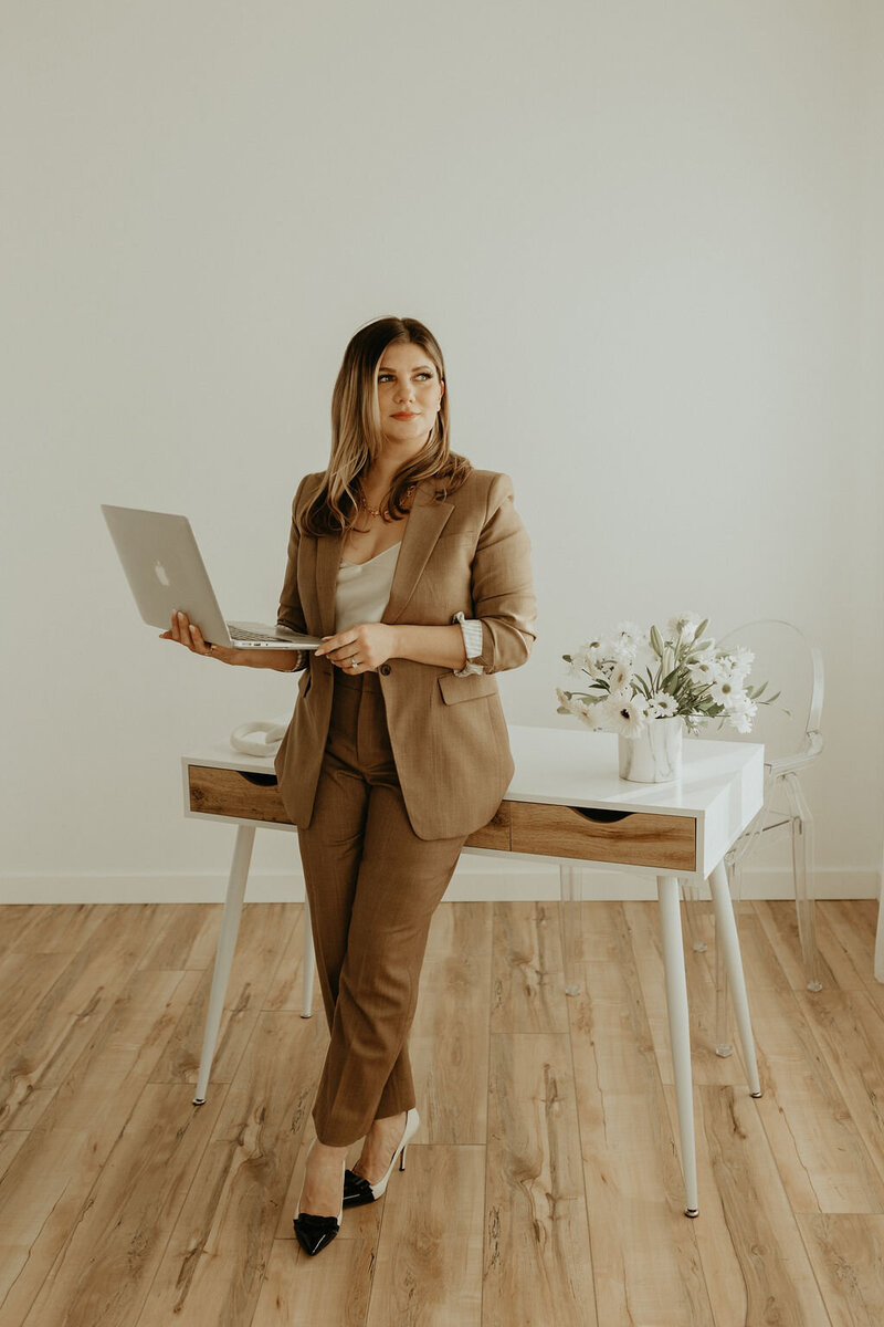 Woman in Beige suit holding laptop